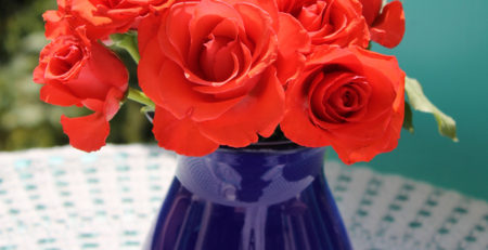 Purple vase with red roses on an outdoor patio table