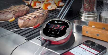 Grill timer, and smart phone next to meat on a BBQ