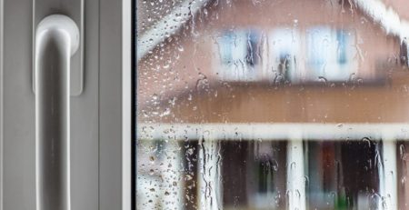 Door handle plus looking through rain soaked window at neighbouring house