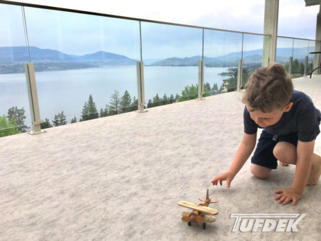 Child playing with toy on vinyl deck with view of lake in background